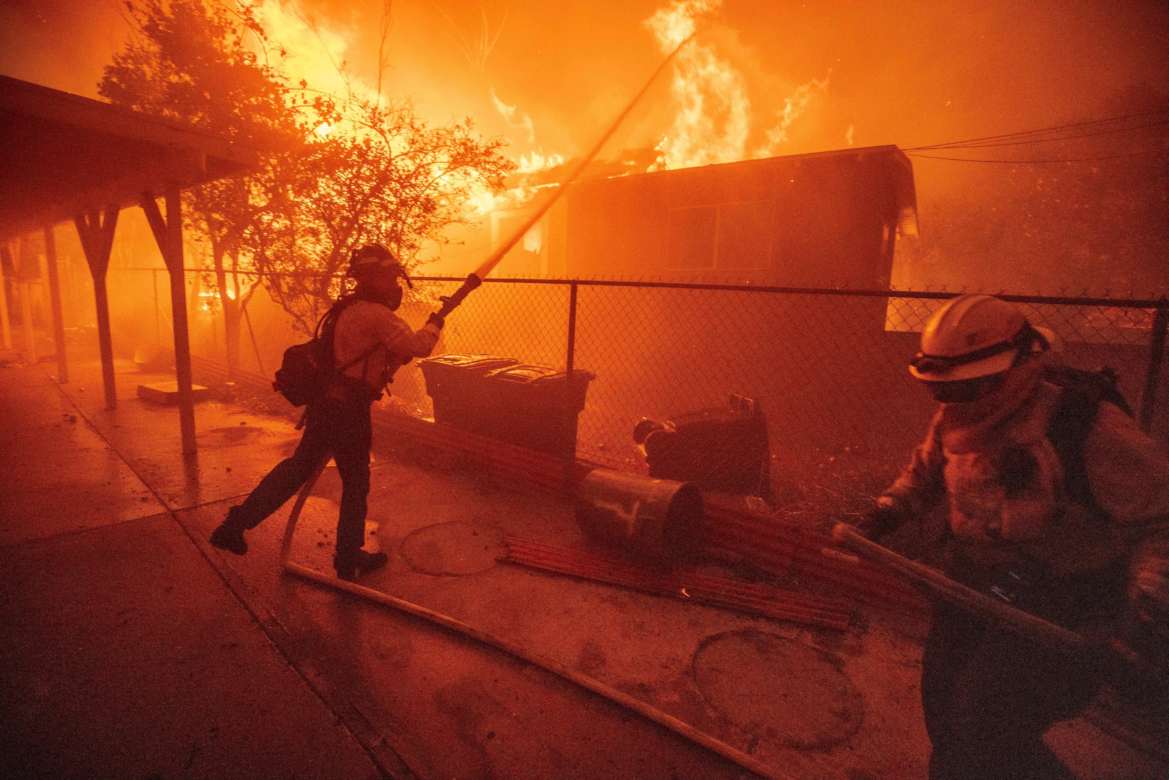 FILE - Firefighters protect a structure as the Eaton Fire advances Jan. 8, 2025, in Altadena, Calif. (AP Photo/Ethan Swope, File)