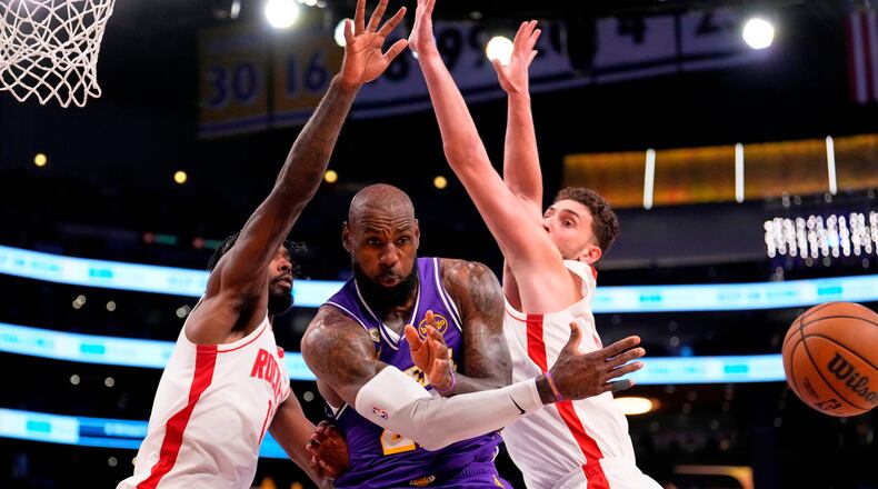 Los Angeles Lakers forward LeBron James, center, passes the ball as Houston Rockets forward Tari Eason, left, and center Alperen Sengun defend during the first half in Game 5 of a first-round NBA playoffs basketball series Wednesday, April 29, 2026, in Los Angeles. (AP Photo/Mark J. Terrill)