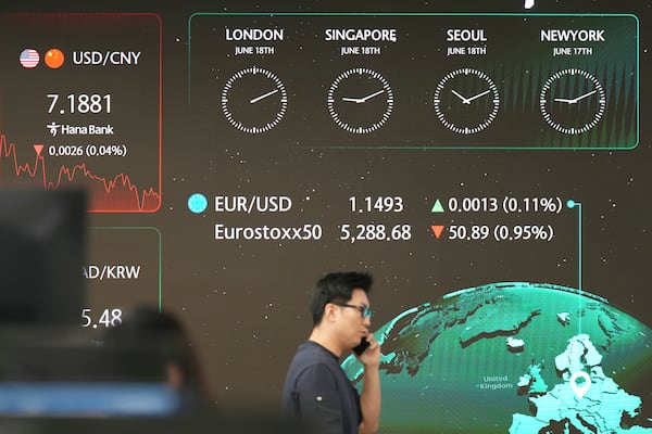 A dealer walks past near the screens showing the foreign exchange rates at a dealing room of Hana Bank in Seoul, South Korea, Wednesday, June 18, 2025. (AP Photo/Lee Jin-man)