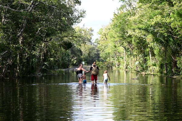 FILE - Dustin Holmes, second from right, holds hands with his girlfriend, Hailey Morgan, while returning to their flooded home with her children Aria Skye Hall, 7, right, and Kyle Ross, 4, in the aftermath of Hurricane Helene, Sept. 27, 2024, in Crystal River, Fla. (AP Photo/Phelan M. Ebenhack, File)
