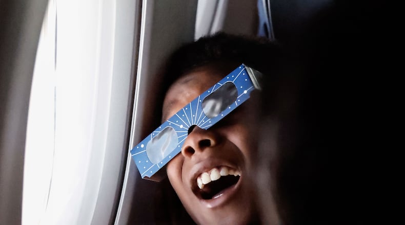 Kyle McSween, 9 from Atlanta, looks out the window during the solar eclipse on Delta Air Line’s flight along the eclipse path from Dallas to Detroit on Monday, April 8, 2024. (Natrice Miller/ Natrice.miller@ajc.com)
