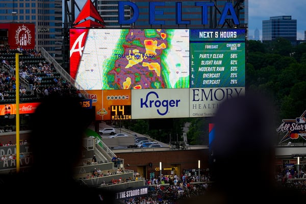 Fans watch the radar displayed before a rain-delayed baseball game between the Atlanta Braves and the Los Angeles Dodgers, Saturday, May 3, 2025, in Atlanta. (AP Photo/Mike Stewart)