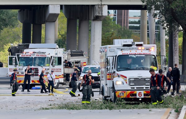 Emergency personnel respond to the area where a small plane crashed on the railroad tracks beneath the overpass near Interstate 95 in Boca Raton, Fla., on Friday, April 11, 2025. (Mike Stocker /South Florida Sun-Sentinel via AP)