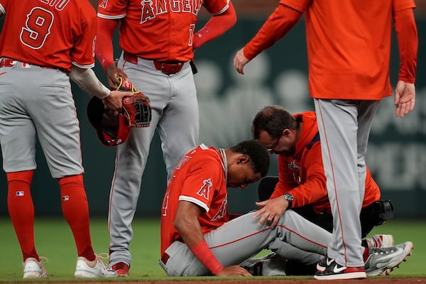 Los Angeles Angels second baseman Christian Moore (4) is helped after being injured fielding a ball hit by Atlanta Braves' Ozzie Albies in the sixth inning of a baseball game, Wednesday, July 2, 2025, in Atlanta. (AP Photo/Mike Stewart)