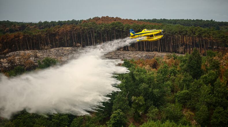 A picture taken from the French Civil Security rescue coordination helicopter shows a firefighting plane dropping water during a wildfire in Le Porge, France, Firday, July 31, 2026. (Sarah Meyssonnier/Pool Photo via AP)