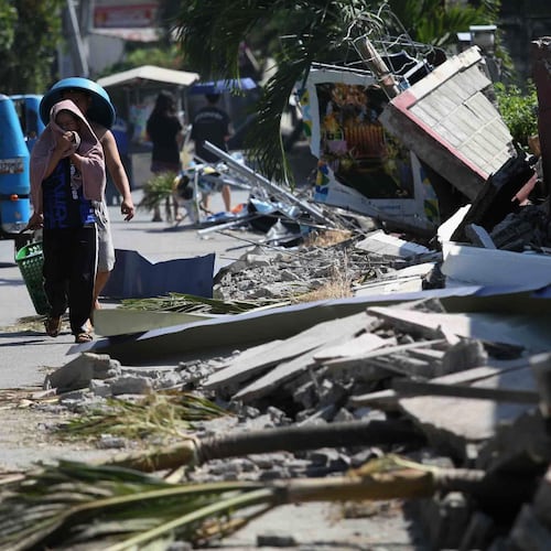 Residents walk past debris from a damaged building in General Santos, southern Philippines, Thursday, June 11, 2026, following Monday's powerful earthquake. (AP Photo/Basilio Sepe)