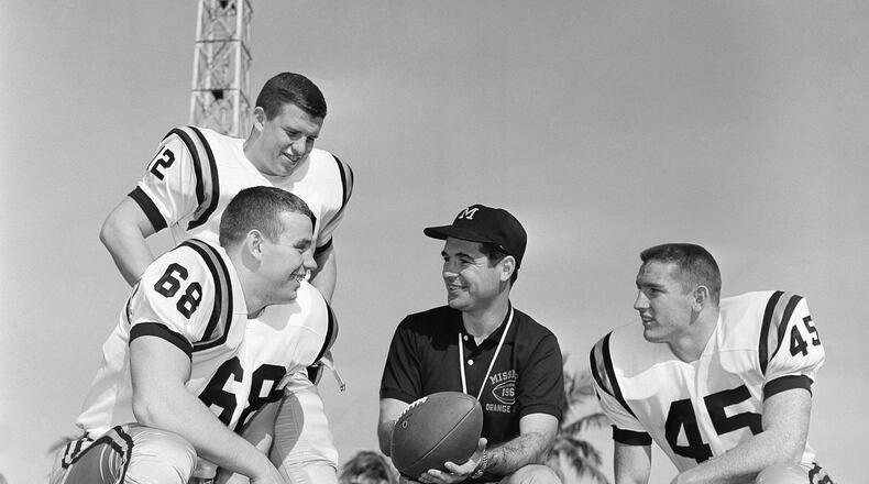 FILE - Missouri head coach Dan Devine, center, meets with three of his girders, Paul Henley (68), guard; Ron Tayler (12), quarterback; and Donnie Smith (45), halfback, in Miami on Dec. 27, 1960. (AP Photo/Earl Shugars, File)