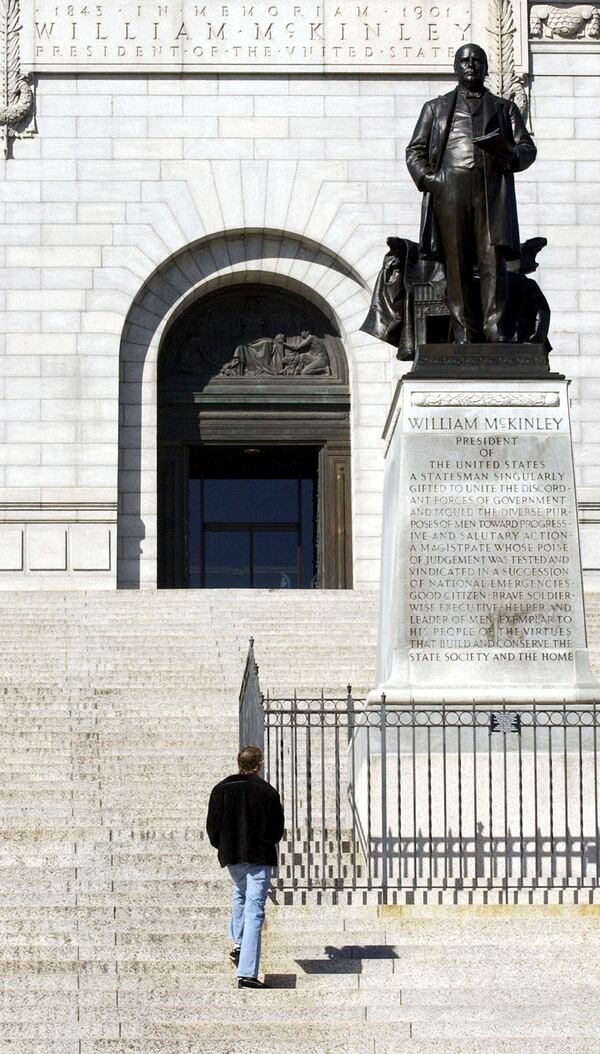 FILE - Roman Feemster, 24, reads the inscription below the bronze statue of President McKinley on the second tier from the bottom of the steps McKinley National Memorial and Museum, Oct. 24, 2003 in Canton, Ohio. (AP Photo/Tony Dejak, File)