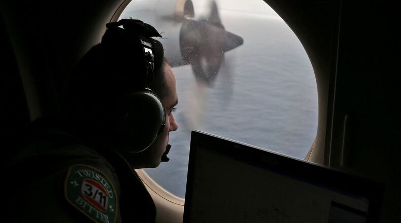 FILE - In this March 22, 2014 file photo, flight officer Rayan Gharazeddine scans the water in the southern Indian Ocean off Australia from a Royal Australian Air Force AP-3C Orion during a search for the missing Malaysia Airlines Flight MH370. A team of international investigators hunting for missing Malaysia Airlines Flight 370 said Tuesday, Dec. 20, 2016 it has concluded the plane is unlikely to be found in a stretch of the Indian Ocean search crews have been combing for two years, and may instead have crashed in an area farther to the north. (AP Photo/Rob Griffith, File)