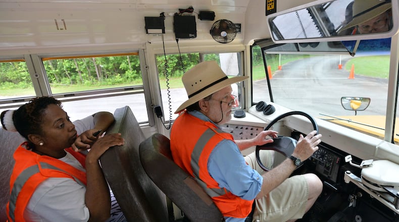 In this photo shot in 2013, Craig Anderson drives a school bus as Elena Bell supervises him on Gwinnett’s driver training course at Gwinnett County Public Schools Bus Driver Training Center in Suwanee. HYOSUB SHIN / HSHIN@AJC.COM