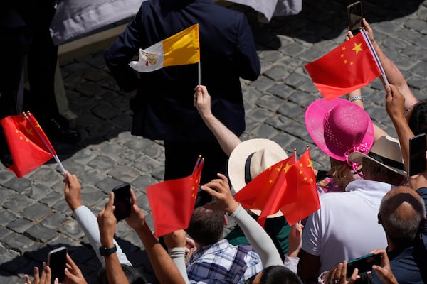 Faithful cheer as they hold China and Vatican flags during the noon Angelus prayer with Pope Leon XIV, in the square in front of the Apostolic Palace for in Castel Gandolfo, Italy, Sunday, July 20, 2025. (AP Photo/Gregorio Borgia)