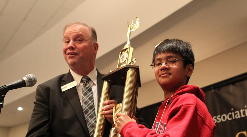 The winner of the State Spelling Bee, Abhiram Kapaganty, stands and holds his trophy up alongside Dr. Sid Chapman, the president of the Georgia Association of Educators in Atlanta, Georgia, on March 17, 2017.