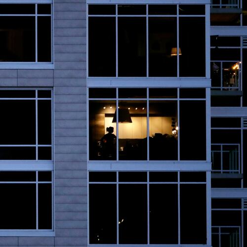 FILE - A person looks out of a window in an apartment building in Kansas City, Mo., May 3, 2020. (AP Photo/Charlie Riedel, File)
