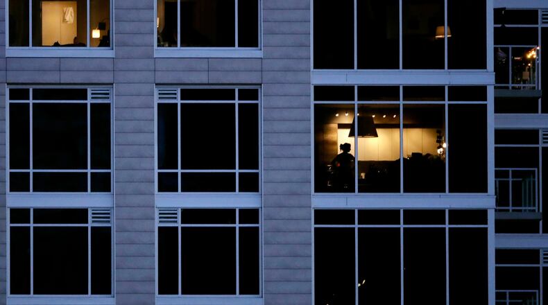 FILE - A person looks out of a window in an apartment building in Kansas City, Mo., May 3, 2020. (AP Photo/Charlie Riedel, File)