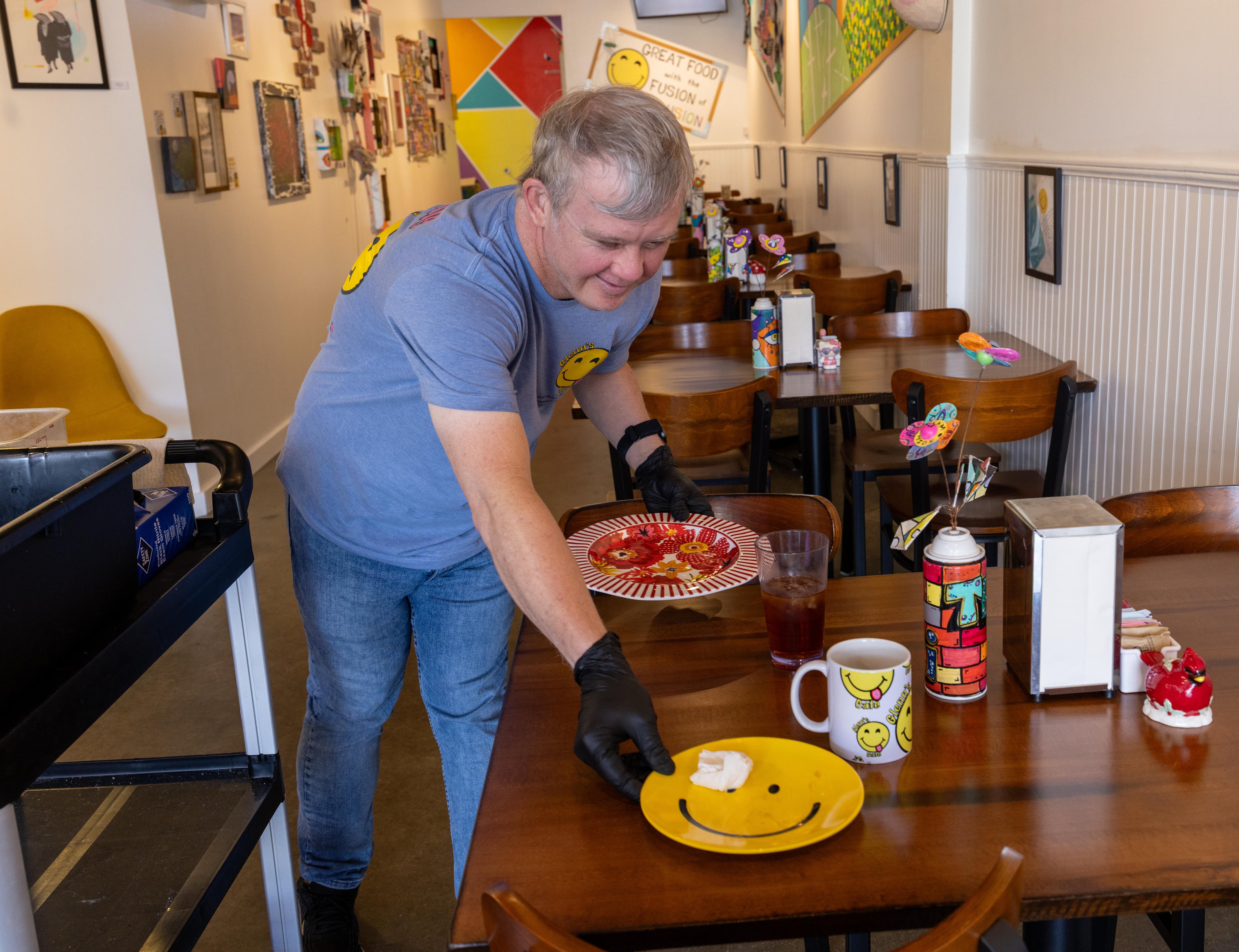 Glenn Hutchinson clears a table at the cafe in Mableton, which was started by Jason and Patricia Walesh to help people with disabilities have jobs and also to raise awareness about special needs people in the community. (Phil Skinner for the AJC)