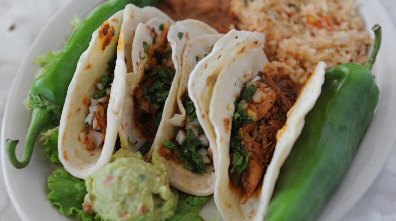 Tacos Al Pastor, four mini flour tortillas filled with chile and pineapple roasted pork, chopped onions and cilantro. served with green chile rice, guacamole and refried beans at Chuy's. (BECKY STEIN)