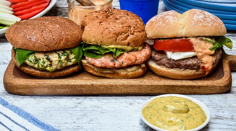 Change your burger routine with a non-beef patty. Pictured, from left to right, are a Blue Cheese-Stuffed Turkey Burger, Salmon Burger with Mustard Dill Sauce, and Lamb Burger with Harissa Mayonnaise. Virginia Willis/For the AJC
(Virginia Willis for The Atlanta Journal-Constitution)