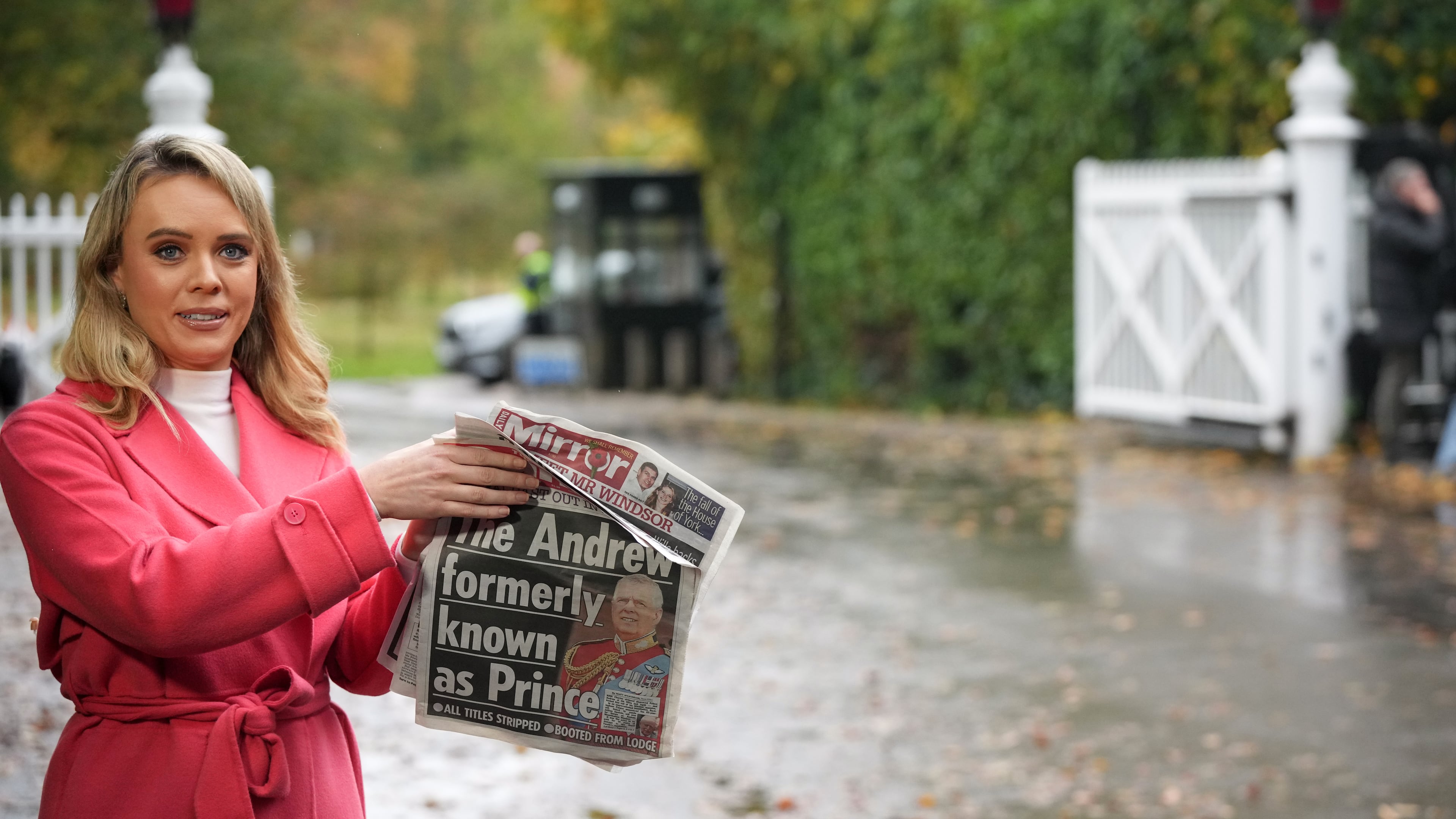 A TV presenter holds a newspaper with a picture of prince Andrew as she talks to the camera at a gate near to the Royal Lodge, following the announcement that Prince Andrew will be stripped of his titles and leave the 30-room mansion he has occupied for more than 20 years in Windsor, England, Friday, Oct. 31, 2025.(AP Photo/Alastair Grant)