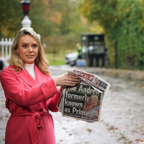A TV presenter holds a newspaper with a picture of prince Andrew as she talks to the camera at a gate near to the Royal Lodge, following the announcement that Prince Andrew will be stripped of his titles and leave the 30-room mansion he has occupied for more than 20 years in Windsor, England, Friday, Oct. 31, 2025.(AP Photo/Alastair Grant)