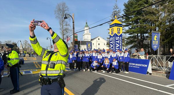 State Police Trooper Cory Hetu takes a selfie with the group of race volunteers at the start of the Boston Marathon Monday, April 21, 2025 in Hopkinton, Mass. (AP Photo/ Jennifer McDermott)