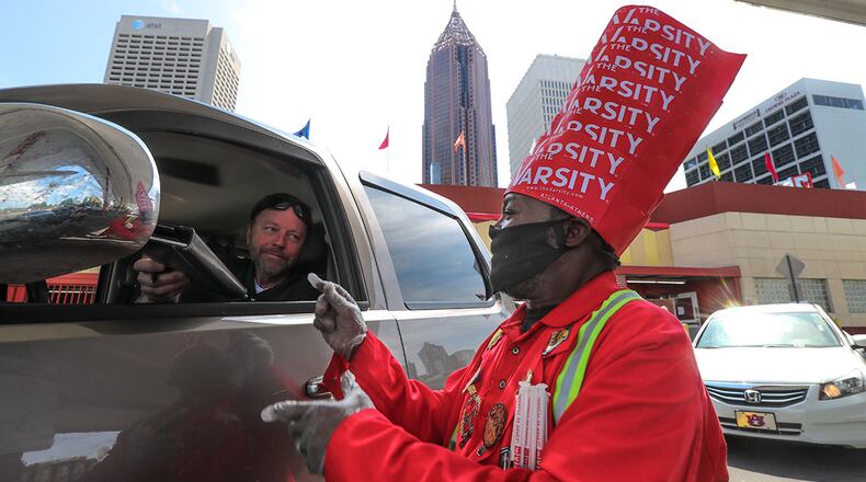 Customer Dave Williams (left) hands over his signed card bill to the Varsity's Fred Stewart on Tuesday, April 28, 2020 at the Varsity located at 61 North Ave NW in downtown Atlanta.