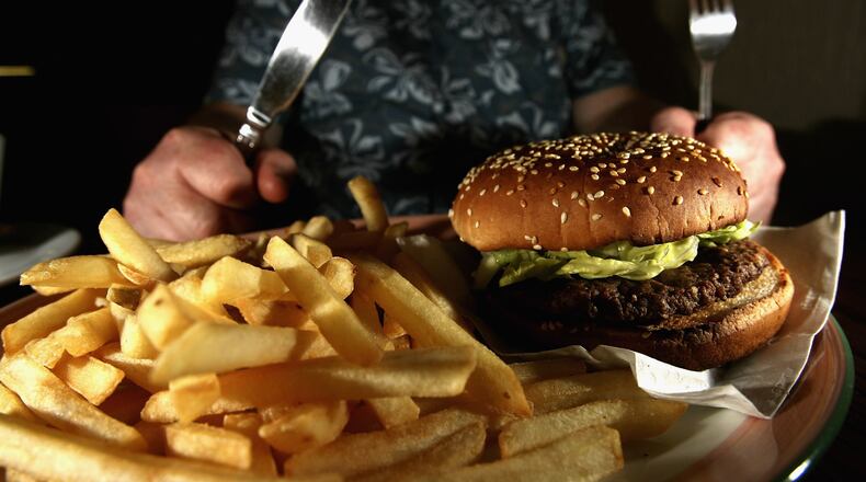 GLASGOW, UNITED KINGDOM - JUNE 07: In this photo illustration a man eats a hamburger and fries in a cafe on June 7,2006 in Glasgow, Scotland. New figures are suggesting that a large proportion of the population is clinically obese. (Photo Illustration by Jeff J Mitchell/Getty Images)