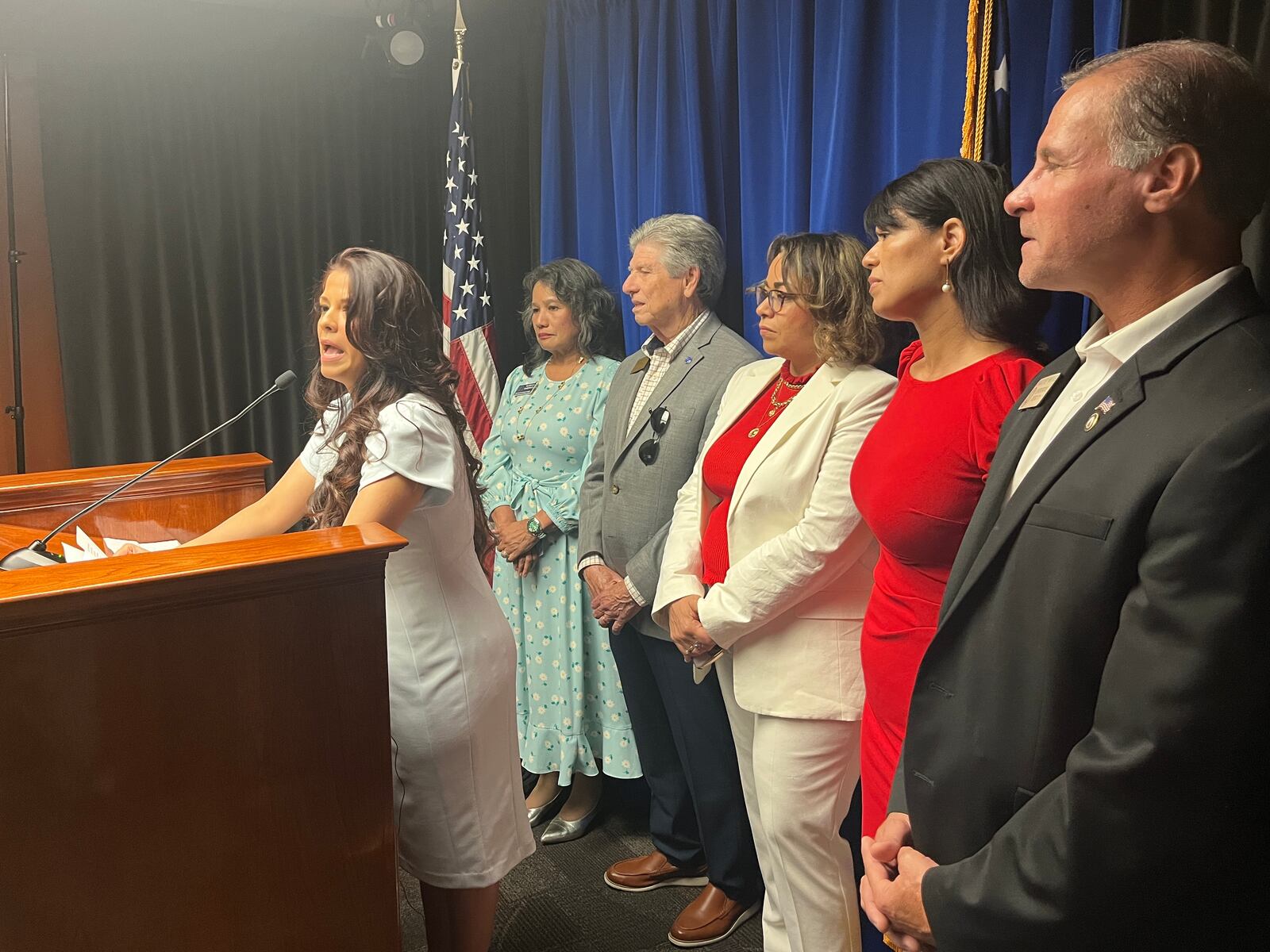 Carli Eli, strategic director for Nuestra Georgia, speaks at the Georgia Capitol on Monday to start the conservative voter group. She was joined by several Hispanic Georgians supporting the effort, including GOP state Rep. Rey Martinez (foreground). (Mark Niesse/mark.niesse@ajc.com)
