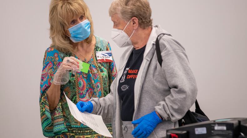 05/18/2020 - Lawrenceville, Georgia  - Poll worker Rae Gilmer (left) wears a face mask and gloves as she assist a voter during early voting at the Gwinnett County Voter Registration and Elections Office in Lawrenceville, Monday, May 18, 2020.  Early voting began May 18 and will last three-weeks, ended June 5. Georgia's Election Day is Tuesday, June 9.(ALYSSA POINTER / ALYSSA.POINTER@AJC.COM)