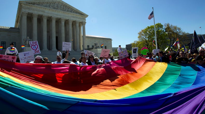 FILE - In this April 28, 2015, file photo, demonstrators stand in front of a rainbow flag of the Supreme Court in Washington, as the court was set to hear historic arguments in cases that could make same-sex marriage the law of the land. Gay and lesbian couples could face legal chaos if the Supreme Court rules against same-sex marriage in the next few weeks. Same-sex weddings could come to a halt in many states, depending on a confusing mix of lower-court decisions and the sometimes-contradictory views of state and local officials. Among the 36 states in which same-sex couples can now marry are 20 in which federal judges invoked the Constitution to strike down marriage bans. (AP Photo/Jose Luis Magana, File)
