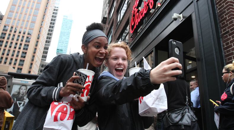 Jaimie Cranford, right, takes a photograph with Mariah Reives outside the Chick-fil-A store in New York on the store's opening day Saturday Oct. 3, 2015. Cranford, originally from South Carolina, and Reives, originally from North Carolina, currently live in New York. (AP Photo/Tina Fineberg)