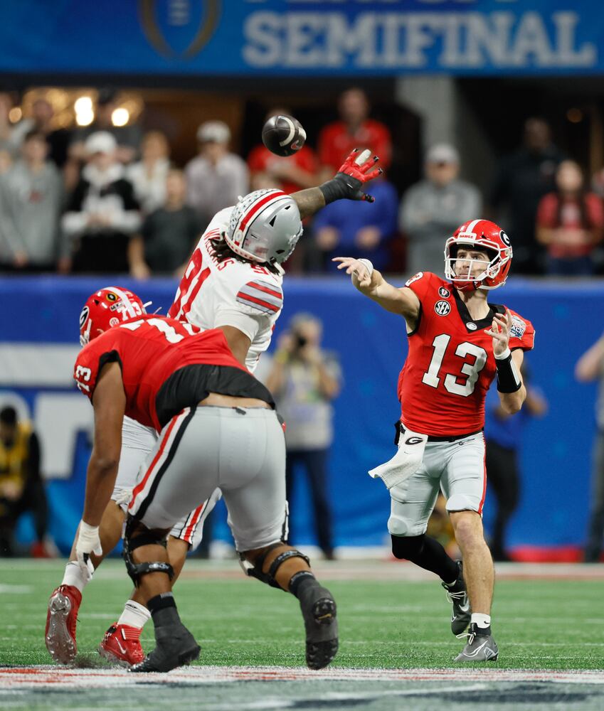 Georgia Bulldogs quarterback Stetson Bennett (13) throws under pressure during the fourth quarter of the College Football Playoff Semifinal between the Georgia Bulldogs and the Ohio State Buckeyes at the Chick-fil-A Peach Bowl In Atlanta on Saturday, Dec. 31, 2022.  Georgia won, 42-41. (Jason Getz / Jason.Getz@ajc.com)