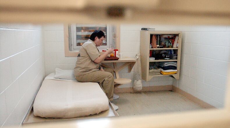 Kelly Gissendaner, the only woman on Georgia’s death row, is shown on July 6, 2004, eating lunch in her 9-by-12 cell at Metro State Prison in Atlanta. The shelving unit at right holds all her possessions. Gissendaner was photographed through the slot in the cell door through which guards pass the prisoner her lunch tray and other items. (Bita Honarvar, The Atlanta Journal-Constitution)