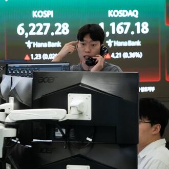 A currency trader talks on the phone near a screen showing the Korea Composite Stock Price Index (KOSPI), top center, and the foreign exchange rate between U.S. dollar and South Korean won, top center left, at the foreign exchange dealing room of the Hana Bank headquarters, in Seoul, South Korea, Friday, April 17, 2026. (AP Photo/Ahn Young-joon)