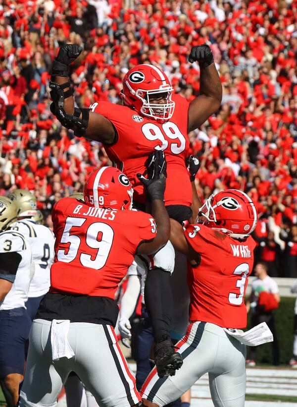 Georgia defensive lineman Jordan Davis (99) gets a hoist in the air by tailback Zamir White (3) and offensive lineman Broderick Jones (59) celebrating his 1-yard touchdown run against Charleston Southern during the first quarter at Sanford Stadium on Saturday, Nov. 20, 2021, in Athens, Georgia. (Curtis Compton/Atlanta Journal-Constitution/TNS)