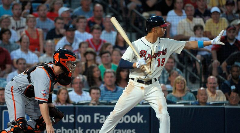 Andrelton Simmons motions to teammate Brian McCann to hold at third base as the ball gets away from San Francisco Giants catcher Buster Posey during the second inning.