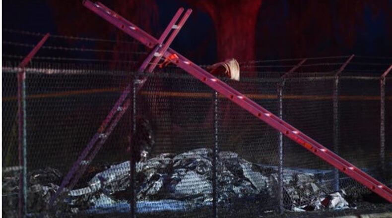 Remnants of a plane carrying nine people lies on the ground near a fence that surrounds Dillingham Airfield in Hawaii. All nine people were killed in the Friday evening crash, authorities said.