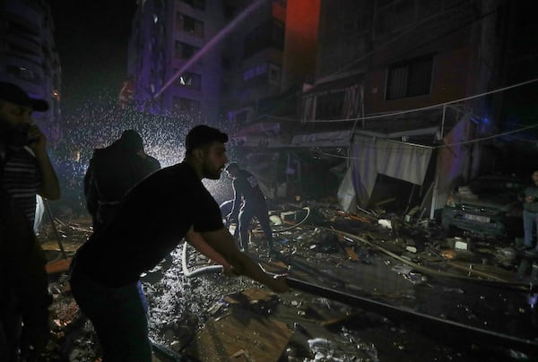 Residents help firefighters who extinguished the flames inside an apartment that was hit by an apparent Israeli airstrike, in the southern port city of Sidon, Lebanon, early Friday, April 4, 2025. (AP Photo/Mohammed Zaatari)