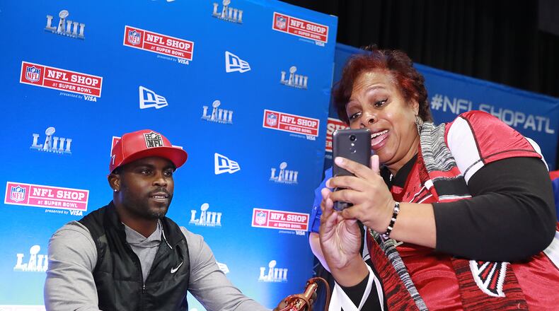 Jan. 31, 2019 Atlanta: Falcons fan Jan Radford snaps a selfie with former Falcons quarterback Michael Vick while he autographs items in the NFL Shop at the Super Bowl Experience on Thursday, Jan. 31, 2019, in Atlanta. Vick has a special edition New Era hat on sale in the NFL Shop.   Curtis Compton/ccompton@ajc.com