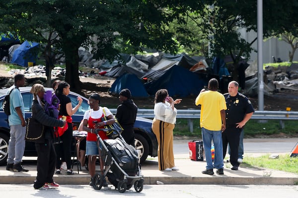 An Atlanta Police officer talks with a man at a large homeless encampment on Pryor Street several days before the city of Atlanta shut it down in May. (Jason Getz / AJC)