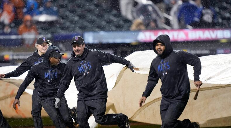 Members of the grounds crew cover the field with the tarp during a rain delay after the fifth inning of a baseball game between the New York Mets and the Atlanta Braves, Friday, April 28, 2023, in New York. (AP Photo/Bryan Woolston)
