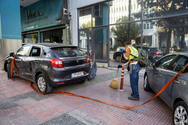 A municipal worker cleans the area outside Hellenic Train headquarters, Greece's main railway company, following a bomb explosion Friday night causing causing limited damage but no injuries, in Athens, Greece, on Saturday, April 12, 2025. (AP Photo/Yorgos Karahalis)