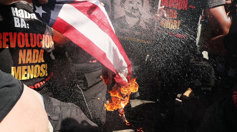 A group tries to burn an American Flag as police move in near the sight of the Republican National Convention (RNC) in downtown Cleveland on the third day of the convention on July 20, 2016 in Cleveland, Ohio. Many people have stayed away from downtown due to road closures and the fear of violence. (Photo by Spencer Platt/Getty Images)