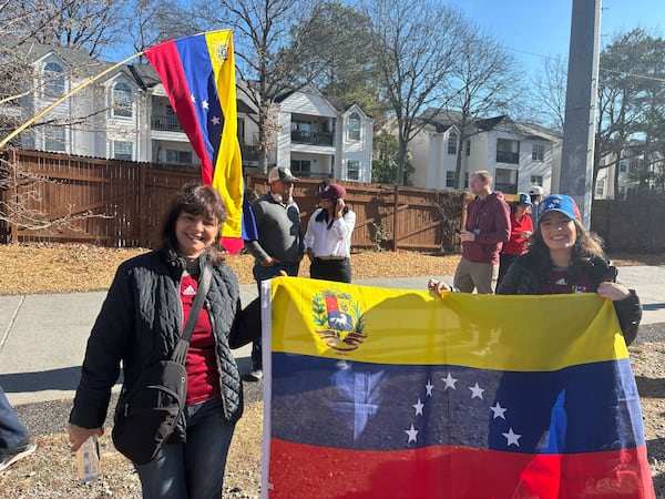 Andrea Paiva (right) and her mother Antonella Dauri hold up the Venezuela flag during a rally Sunday on the Atlanta Beltline near Monroe Drive. (David Aaro/AJC)