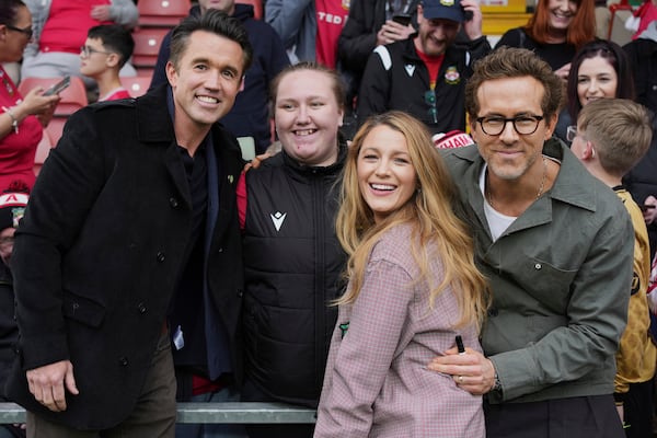 Wrexham co-owners Ryan Reynolds, right, his wife Blake Lively, second right, and Rob McElhenney, left, pose with fans before the English League One soccer match between Wrexham and Charlton Athletic at the Racecourse ground in Wrexham, Wales, Saturday, April 26, 2025. (AP Photo/Jon Super)