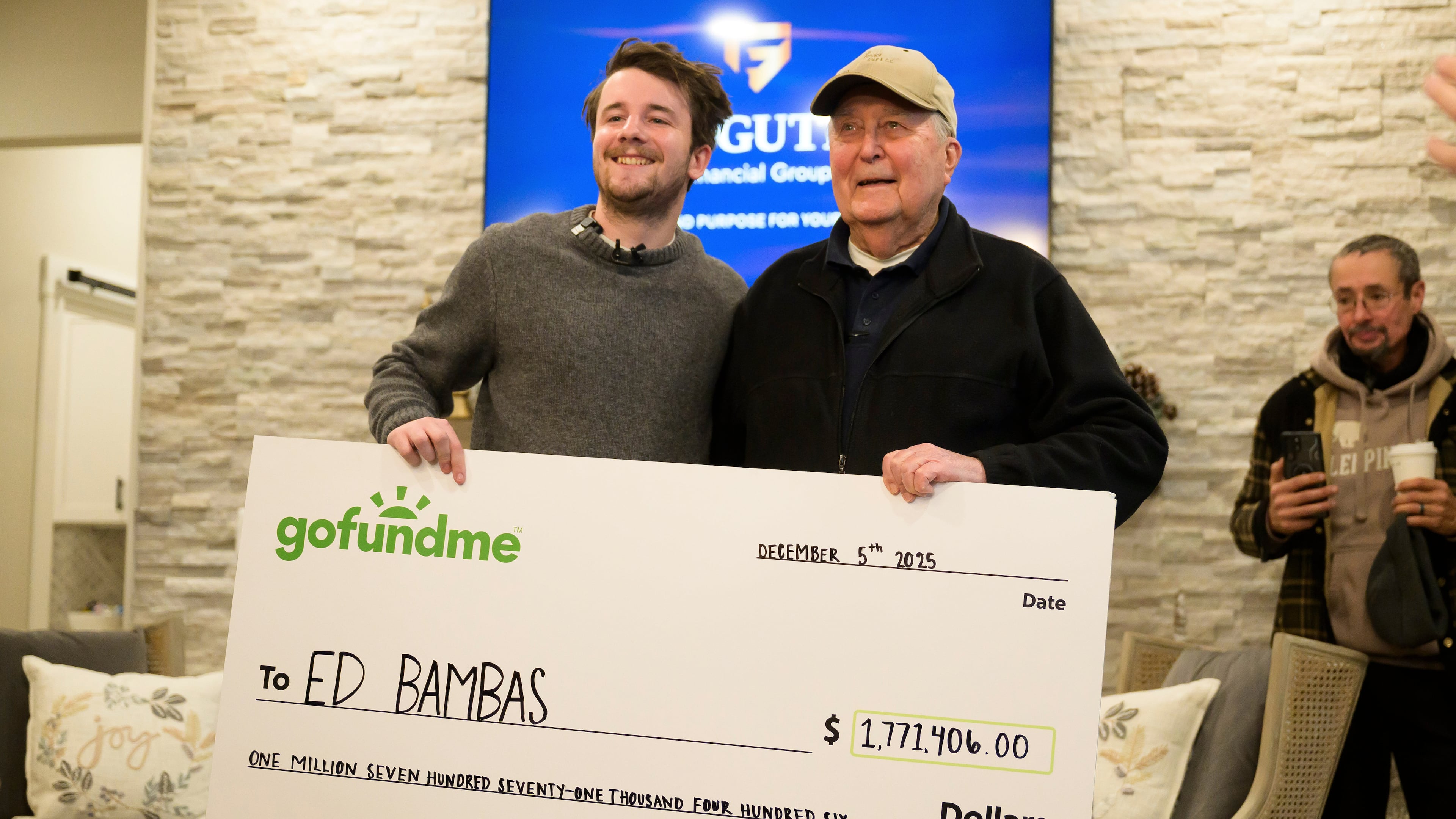 Influencer Samuel Weidenhofer, left, poses for a photo with Ed Bambas, right, the 88-year-old Brighton resident who is the recipient of over $1.7 million after a viral Gofundme campaign was started by Weidenhofer, after the amount is revealed to Bambas, Friday, Dec. 5, 2025, in Brighton, Mich. (Katy Kildee/Detroit News via AP)