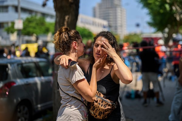 People react next to the site of a direct missile strike launched from Iran in Tel Aviv, Israel, on Sunday, June 22, 2025. (AP Photo/Bernat Armangue)