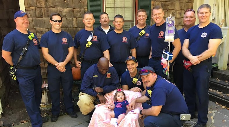Multiple members of the Alpharetta Fire Department surround 11-month-old Raven Nell Raines outside of her home on Sherry Lane.