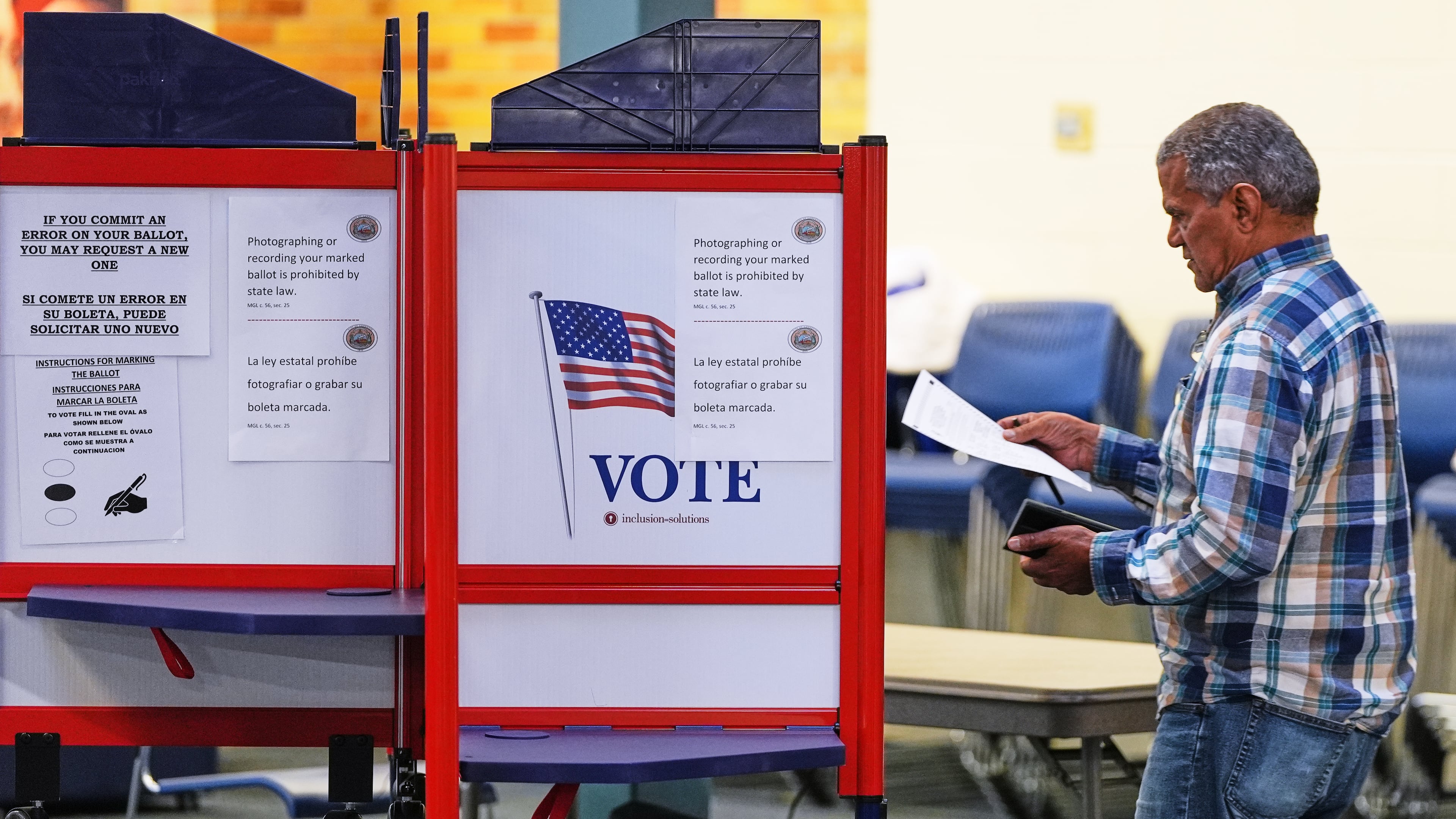 FILE - A voter carries his ballot to a booth at a polling station, Nov. 4, 2025, in Lawrence, Mass. (AP Photo/Charles Krupa, File)