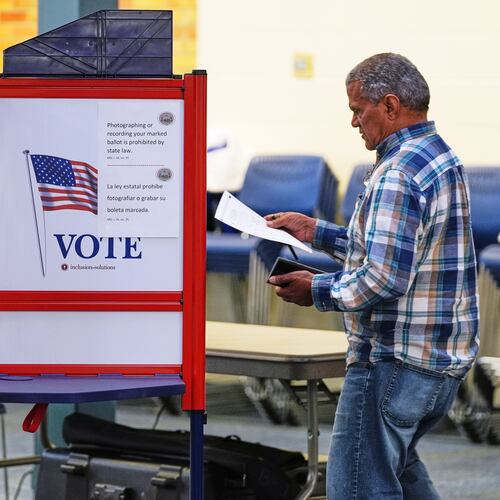 FILE - A voter carries his ballot to a booth at a polling station, Nov. 4, 2025, in Lawrence, Mass. (AP Photo/Charles Krupa, File)