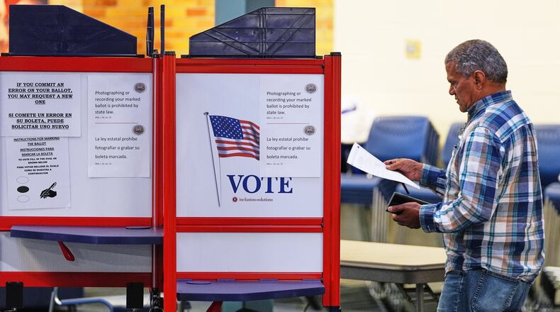 FILE - A voter carries his ballot to a booth at a polling station, Nov. 4, 2025, in Lawrence, Mass. (AP Photo/Charles Krupa, File)
